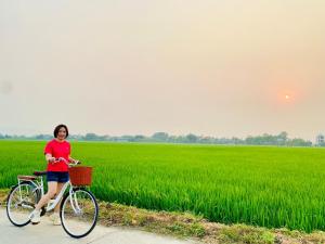 Eine Frau, die vor einem Reisfeld Fahrrad fährt. in der Unterkunft Lala Boutique Villas in Ninh Bình