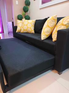 un sofá negro con almohadas amarillas en la sala de estar. en Milagrosa(SMDC wind residences), en Tagaytay