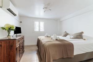 Habitación blanca con cama y TV en BEAU REZ DE JARDIN- Cannes Suquet - Clim- Calme - Lumineux- 15 minutes Palais des Festival, en Cannes