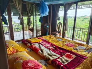 a bedroom with a bed with a blanket on it at Banlung Hill Top House &Trekking in Phumĭ Pôy