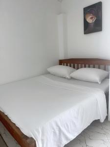 - un lit avec des draps et des oreillers blancs dans l'établissement Mudzini one bedroom, à Mombasa