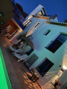 un gran edificio blanco con sillas y sombrilla en Casa Morayma, Lecrin, Granada (Adult Only Small Guesthouse), en Acequias