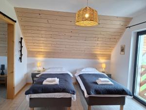 two beds in a room with a wooden ceiling at Domki Szczyt Beztroski - Sauna, Jacuzzi in Nowy Targ
