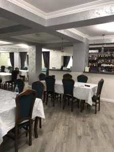 a dining room with white tables and chairs and tablesearcher at Pensiunea Cascada Putnei in Lepşa