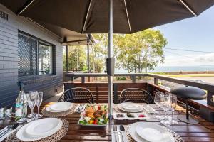 una mesa con platos de comida y una sombrilla en 549 Luxury Apartments, en Hervey Bay