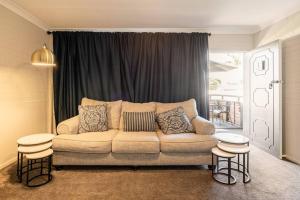 ein Wohnzimmer mit einem Sofa und 2 Hockern in der Unterkunft 549 Luxury Apartments in Hervey Bay