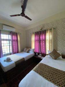 a bedroom with two beds and pink curtains at Hotel Safari Suite in Sauraha