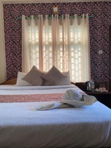 a bedroom with a bed with white sheets and a window at Hotel Safari Suite in Sauraha