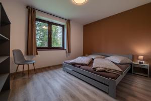 a bedroom with a bed and a chair and a window at White Hawk - Vila Sokolík in Lazisko