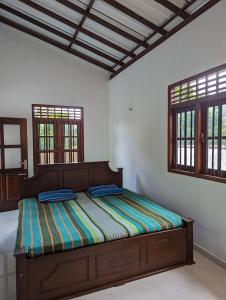 a bed in a room with two windows at Uma Guest House in Kahawa