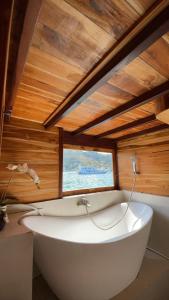 eine große weiße Badewanne in einem Zimmer mit Fenster in der Unterkunft DAV Travels in Labuan Bajo