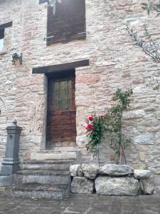 a stone building with a wooden door and some flowers at Maison en Pierre in Fiastra