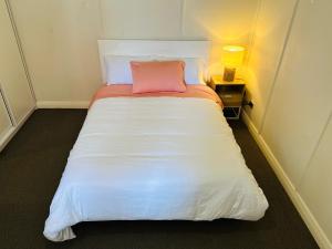 Una cama en una habitación pequeña con una almohada rosa. en Bahay on Marsh, en Armidale
