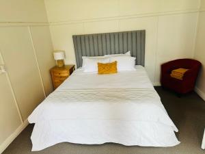 1 dormitorio con 1 cama blanca grande con almohada naranja en Bahay on Marsh, en Armidale