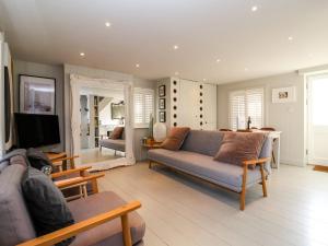 ein Wohnzimmer mit einem Sofa und einem TV in der Unterkunft Mariners Cottage in Aldeburgh