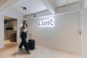 a woman walking past a store with a sign on a wall at The Lair Bangkok - 3mins walk to ICON SIAM in Bangkok