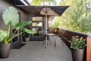 a patio with a table and chairs and an umbrella at Cypress BnB in Hervey Bay