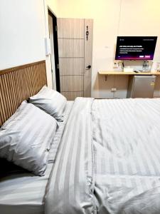 un letto con lenzuola bianche e un computer su una scrivania di Pk house and cosy - Sala102 a Betong