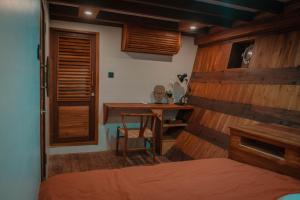 een slaapkamer met een houten muur met een tafel en een bureau bij DAV Travels in Labuan Bajo