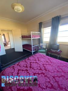 a bedroom with a pink bed and a bunk bed at Inglewood Cottage in Adaminaby