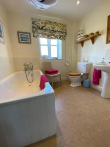 a bathroom with a tub and a toilet and a sink at Lower Farm Cottage in Beaminster
