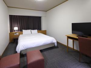 钏路Dormy Inn PREMIUM Kushiro的配有床、书桌和电视的酒店房间