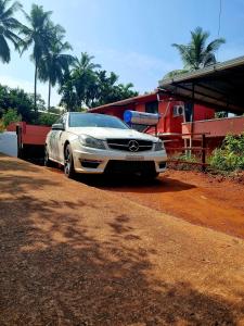 a white car parked in front of a building at Maison Parnakuti Adigas Homestay Dharmasthala in Dharmastala