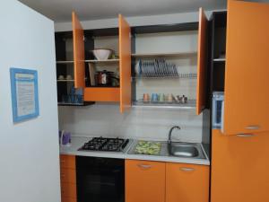 uma pequena cozinha com armários laranja e um lavatório em Cortile Maggiore Home em Cefalù
