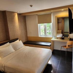 a bedroom with a bed and a desk and a window at M Hotel in Jakarta