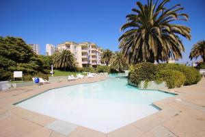 una piscina con una palmera y un edificio en Resort hippocampus en Concón