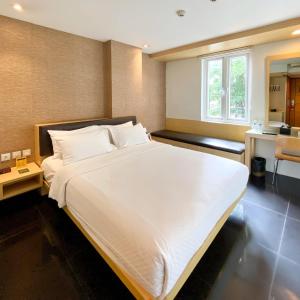 a large white bed in a room with a kitchen at M Hotel in Jakarta