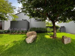a yard with rocks and a tree and a house at Jackal Creek Golf Estate in Roodepoort