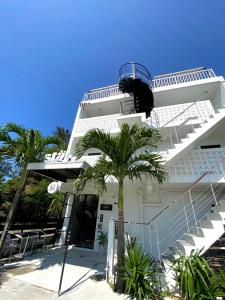 a white building with stairs and a palm tree at Stäy Hotel in Nago