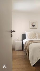 een witte slaapkamer met een bed en een nachtkastje bij Suite Maritim - Zijdelings zeezicht op 50m van strand en zee in Knokke-Heist