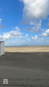 una playa de arena con un edificio en el centro en Suite Maritim - Zijdelings zeezicht op 50m van strand en zee, en Knokke-Heist