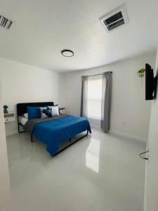 a bedroom with a blue bed in a white room at White house 2 in Lehigh Acres