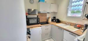 eine kleine Küche mit einer Spüle und einer Mikrowelle in der Unterkunft LaConciergerieJonzac Appart 1 chambre Cocooning in Jonzac