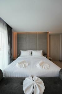 un grande letto bianco con decorazioni a fiocco di โรงแรมออร่า สงขลา a Hat Yai