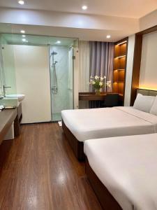 a hotel room with two beds and a bathroom with a shower at The Cosy Inn Hanoi in Hanoi