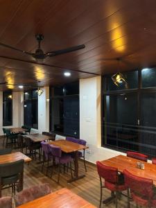 a restaurant with wooden tables and chairs and windows at Lemonade Inn in Chamba