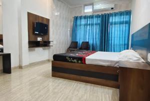 een slaapkamer met een bed met 2 stoelen en een televisie bij Goroomgo Hotel The Nirmala Palace Ayodhya-Near Ram Mandir in Ayodhya