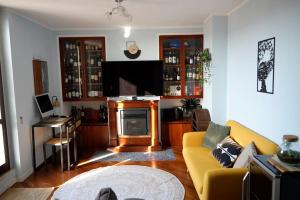 a living room with a yellow couch and a television at Attico 26 in Perugia