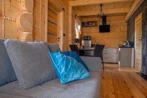 a couch with blue pillows sitting in a living room at Chata Czarny Kot z jacuzzi i sauną in Janowice Wielkie
