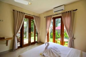 a bedroom with a bed and a large window at Gria Sindhu Homestay Sidemen by AGATA in Sidemen
