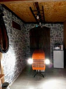 an orange chair in a room with a stone wall at La Grange de Paul au Domaine du Reuze in Winnezeele
