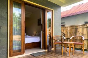 a balcony with a bed and a table and chairs at Gria Sindhu Homestay Sidemen by AGATA in Sidemen