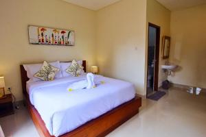 a bedroom with a large bed with white sheets at Gria Sindhu Homestay Sidemen by AGATA in Sidemen +13 photos