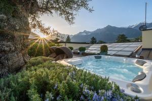 a hot tub in a garden with mountains in the background at Hotel Mignon Meran Park & Spa in Merano