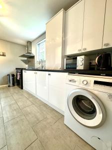 a white kitchen with a washing machine in it at The Standalone - 4 Bedroom Home with Garden by Wild in London