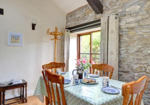 a dining room with a table and a stone wall at Owl Cottage in Llanerchymedd